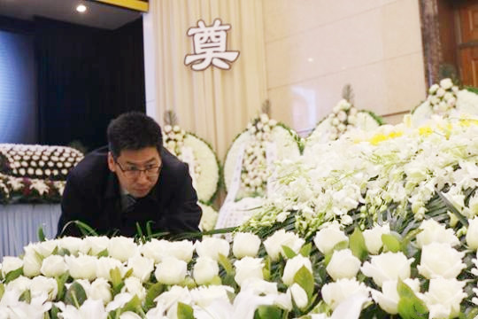 靳中学在整理逝者遗体身旁的鲜花
